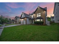 Charming two-story home featuring manicured lawn, brick facade, and two-car garage at 773 Minor Oaks Nw Run, Lilburn, GA 30047