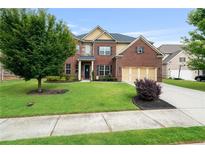 Lovely two-story brick home with a well-manicured lawn, mature trees, and a two-car garage at 3352 Stone Point Way, Buford, GA 30519