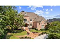 Stunning brick home featuring an elegant entrance with a balcony, landscaped yard, and meticulously maintained lawn at 8295 St Marlo Fairway Dr, Duluth, GA 30097
