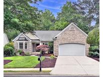 Charming brick home featuring an attached garage, well-manicured lawn, and beautiful landscaping at 554 Grand Ashbury Ln, Sugar Hill, GA 30518