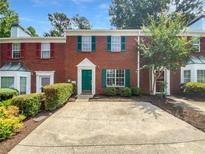 Traditional brick townhouse with a green front door and manicured landscaping at 688 Anderson Walk, Marietta, GA 30062