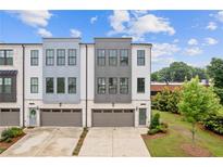 Modern townhome with a mix of white and gray exterior paint, gray brick accents, and a two car garage at 2808 Maddison Towns Ave, Norcross, GA 30071