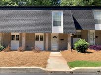 Traditional brick townhouse with a neatly manicured lawn and sidewalk leading to the front door at 5570 Chemin De Vie, Atlanta, GA 30342
