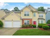 Charming two-story home featuring a red door, manicured lawn and a two car garage at 606 Hay Meadow, Acworth, GA 30102