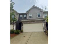 Two story townhome with a large garage, concrete driveway and neutral colored brick and siding at 2778 Wild Laurel Ct, Norcross, GA 30071