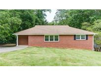 Charming brick home featuring manicured lawn, windows and mature trees at 256 Indian Trl, Marietta, GA 30068