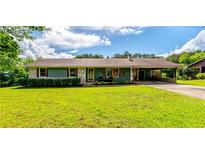 Charming single-story home featuring a well-manicured lawn, attached carport, and inviting front porch seating area at 27 Ansley Nw Way, Cartersville, GA 30121
