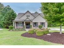 Charming brick home with well-manicured lawn, mature trees, and inviting front porch with outdoor seating at 7070 Concord Mountain Trl, Cumming, GA 30028