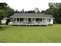 Charming home featuring a long porch, lush lawn, and mature trees at 124 Wynn Rd, Mcdonough, GA 30252