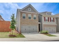 Charming two-story brick home featuring an attached two-car garage and manicured lawn at 7682 Baron Rd, Fairburn, GA 30213