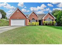 Charming, one-story brick home with well-maintained lawn, a two-car garage, and lush landscaping at 1627 Amhearst Walk Rd, Lawrenceville, GA 30043