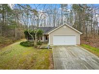 Charming single-story home with a two-car garage and a well-maintained front lawn in a wooded setting at 300 Lakeside Dr, Covington, GA 30016
