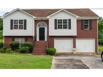 Two-story home with brick and siding, featuring an attached two-car garage and landscaped front yard at 4527 Berline Dr, Lithonia, GA 30038