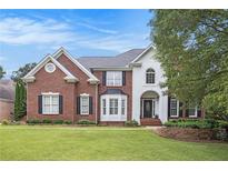 Beautiful brick and stucco home featuring a manicured lawn and classic architectural details at 650 Garden Wilde Place, Roswell, GA 30075