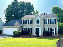 Charming two-story home with a manicured lawn, black shutters, and a two-car garage at 4780 Agate Dr, Johns Creek, GA 30022