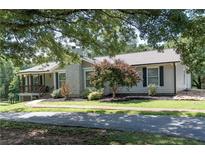 Charming single-story home featuring a stone chimney, covered porch, mature trees, and landscaped front yard at 8321 Banks Mill Rd, Douglasville, GA 30135