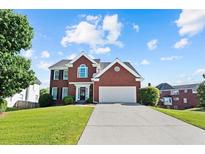 Charming two-story red brick home with a two-car garage and well-manicured lawn on a beautiful day at 3226 Masters Pass Ln, Snellville, GA 30039