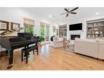 Spacious living room with a grand piano, fireplace, built-in shelving and bright windows at 1045 Endeavour Ct, Marietta, GA 30064