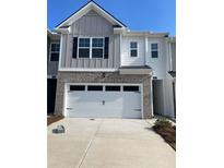 Charming townhome featuring a two-car garage, brick accents, and a well-maintained front yard at 1315 Aura Ln, Lawrenceville, GA 30045