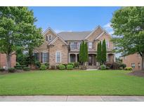 Charming brick home featuring lush green lawns, mature trees, and architectural details at 1241 Edgebrook Ln, Snellville, GA 30078