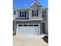 Charming two-story townhome featuring a stone facade and a spacious two-car garage at 1311 Aura Ln, Lawrenceville, GA 30045