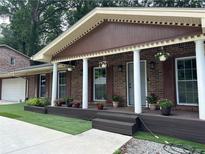Charming brick home featuring a covered front porch with stately columns and colorful flowerpots at 4807 Greenway Rd, Norcross, GA 30071