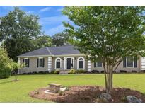 Charming single story home with well maintained lawn, mature trees and appealing stone bench at 2265 Colony Dr, Canton, GA 30114