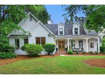 Charming painted brick home with manicured lawn, dormers, inviting front porch and double-door front entry at 6655 Manchester Pl, Cumming, GA 30040