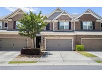 Brick townhouse with a two car garage and a well maintained front yard at 11686 Davenport Ln, Alpharetta, GA 30005