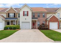 Charming townhome featuring a one car garage, red front door, manicured lawn, and inviting curb appeal at 2924 Greyhawk Ln, Cumming, GA 30040
