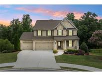 Charming two-story brick home with a three-car garage and landscaped front yard at sunset at 2330 Cheatham Creek Ct, Cumming, GA 30040