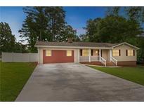 Charming one-story home with red accents, an attached garage, mature trees and a spacious concrete driveway at 25 Carriage Ct, Stockbridge, GA 30281
