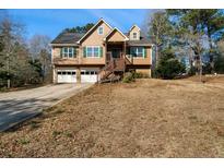 Two-story home with a two-car garage, and a wooden staircase leading to the front door at 120 Paces Lakes Pt, Dallas, GA 30157
