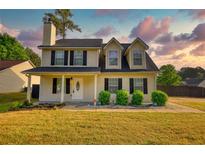 Charming two-story home with black shutters, a covered porch, landscaped yard, and fresh green grass at 1700 Conductor Ln, Conyers, GA 30013