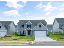 Charming two-story home with gray siding, stone accents, a well-manicured lawn, and an attached two-car garage at 117 Oliver Dr, Locust Grove, GA 30248