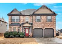 Charming brick home featuring a red front door, a two-car garage, and well-maintained landscaping at 845 Nevis Way, Mcdonough, GA 30253