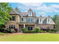 Charming two-story home with a manicured lawn, professional landscaping and mixed brick and stacked stone details at 1771 Silvergrass Ln, Grayson, GA 30017