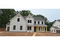 New construction shows a bright, two-story farmhouse-style home with a covered front porch and black-framed windows at 4615 Greyson Manor Dr, Cumming, GA 30041