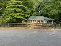 Charming home featuring a well-kept yard, complete with a wooden fence and beautiful mature trees at 2225 Harold Se Ln, Smyrna, GA 30080