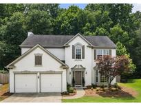 Charming two-story home boasts a two-car garage and manicured front yard with mature trees at 144 Nocatee Trl, Woodstock, GA 30188