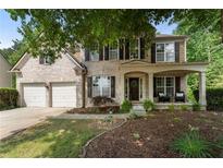 Charming two-story brick home with a covered front porch, two-car garage, and well-manicured lawn at 5828 Paliser Trce, Sugar Hill, GA 30518