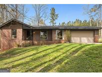 Charming brick home with attached garage and spacious front yard with healthy green grass at 779 Pinehurst Dr, Fairburn, GA 30213