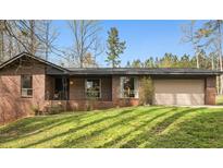Charming brick home featuring a well-manicured front lawn and an attached two car garage at 779 Pinehurst Dr, Fairburn, GA 30213