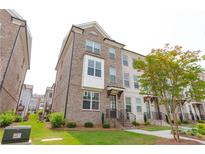 Charming three-story brick townhome with well-maintained landscaping and inviting front entrance at 3195 Bartee Walk, Suwanee, GA 30024