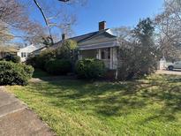 Charming single-story home featuring mature landscaping and a welcoming covered porch at 5121 Newark Ave, Clarkdale, GA 30111