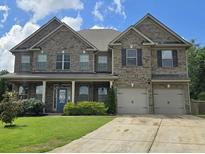 Charming two-story brick home featuring a two-car garage, manicured lawn, and inviting front porch at 5445 Whisper Ct, Cumming, GA 30028