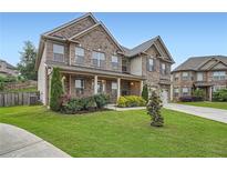 Charming two-story brick home with a well-manicured lawn and blooming flower beds at 5445 Whisper Ct, Cumming, GA 30028