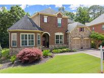 Charming two-story brick home featuring a manicured lawn, stone accents, and a two-car garage at 4896 Locklear Way, Marietta, GA 30066