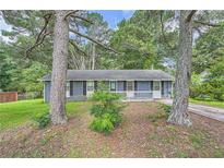 Charming single-story home featuring a gray brick exterior, a small front porch, and mature shade trees at 62 Sunny Ln, Villa Rica, GA 30180