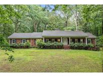 Charming brick home with a covered porch, surrounded by a lush green lawn and mature trees at 286 Hilton Way Way, Canton, GA 30114